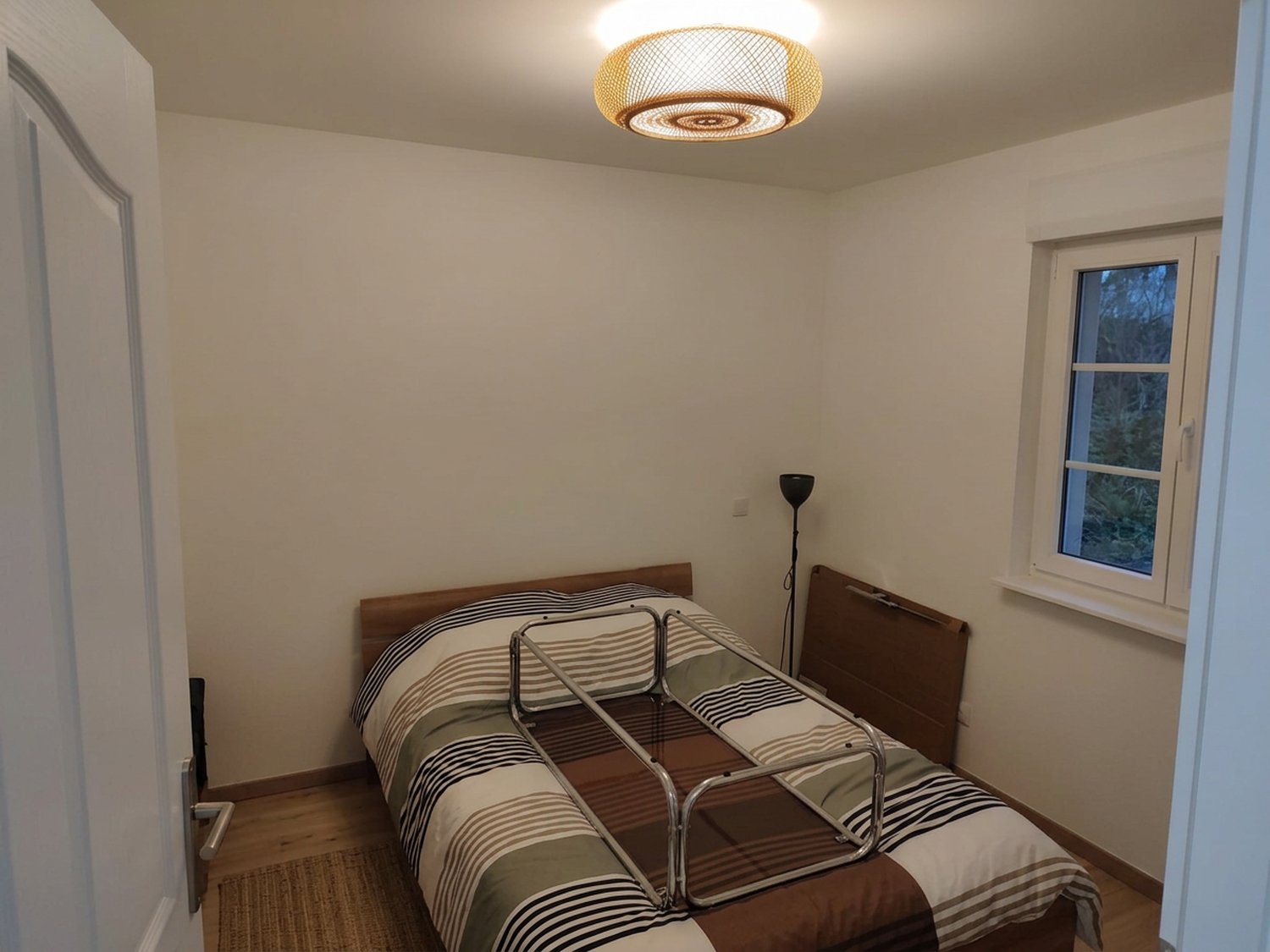 Chambre éclairée par un plafonnier en rotin tressé, appartement à Saint-Louis