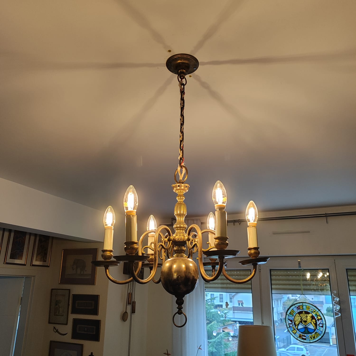 Lustre en laiton doré à six lumières raccordé au plafond d'un séjour avec baie vitrée